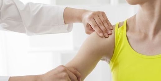 Un trabajador sanitario coloca una mano sobre el hombro de un paciente en un entorno clínico luminoso.