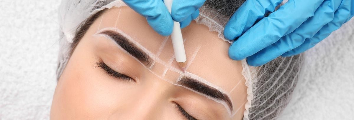 Manos enguantadas aplicando un tratamiento cosmético en la frente de una mujer con los ojos cerrados.