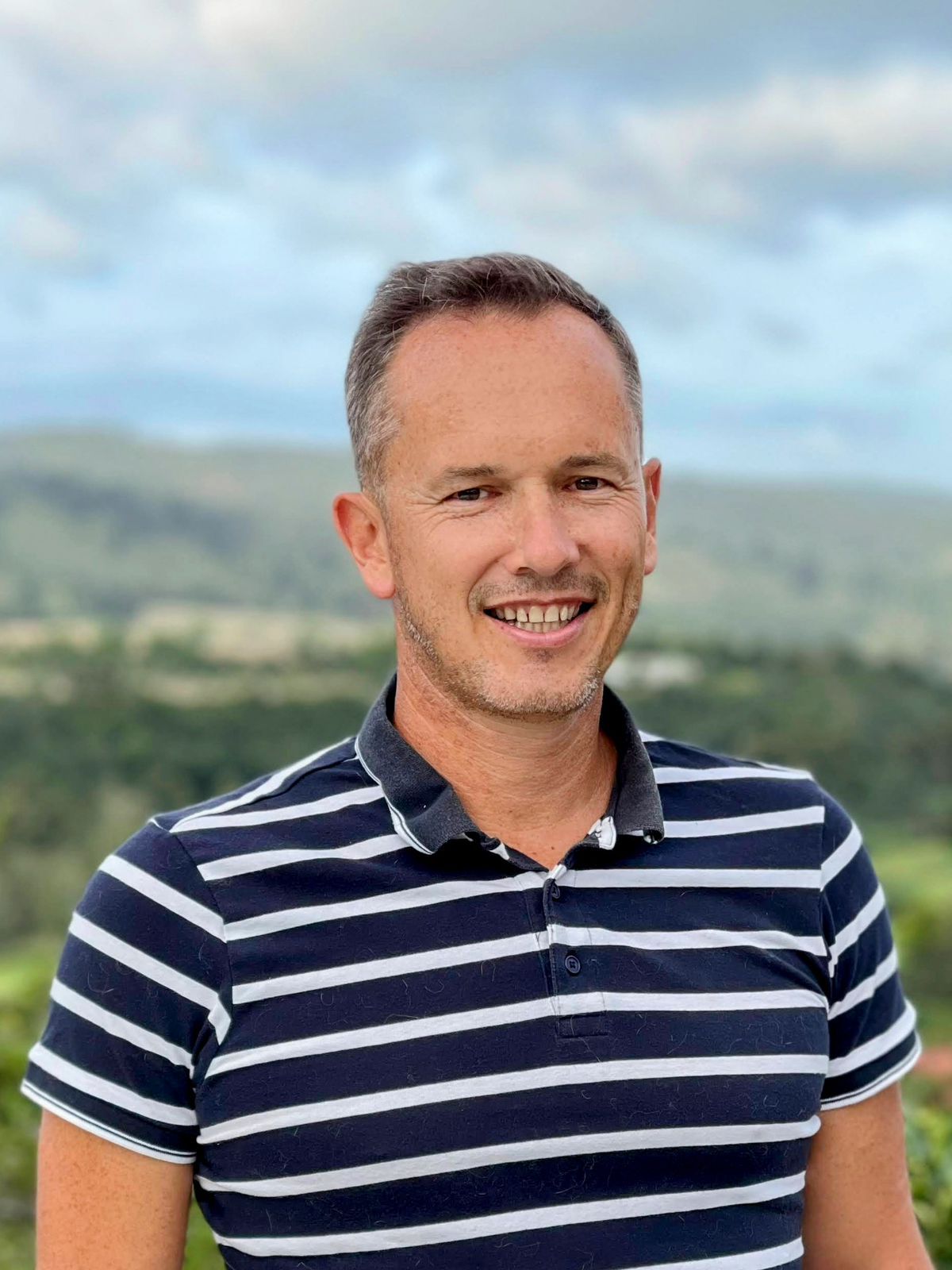 A man in a striped shirt is smiling for the camera.