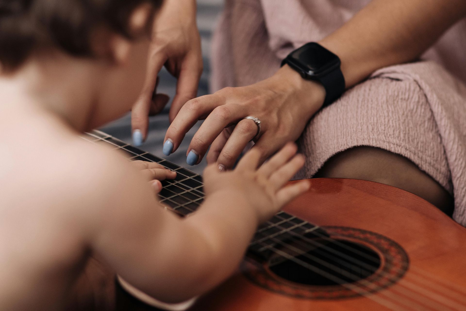 Hombre tocando la guitarra, mujer sosteniendo a un bebé en el sofá, sala de estar.