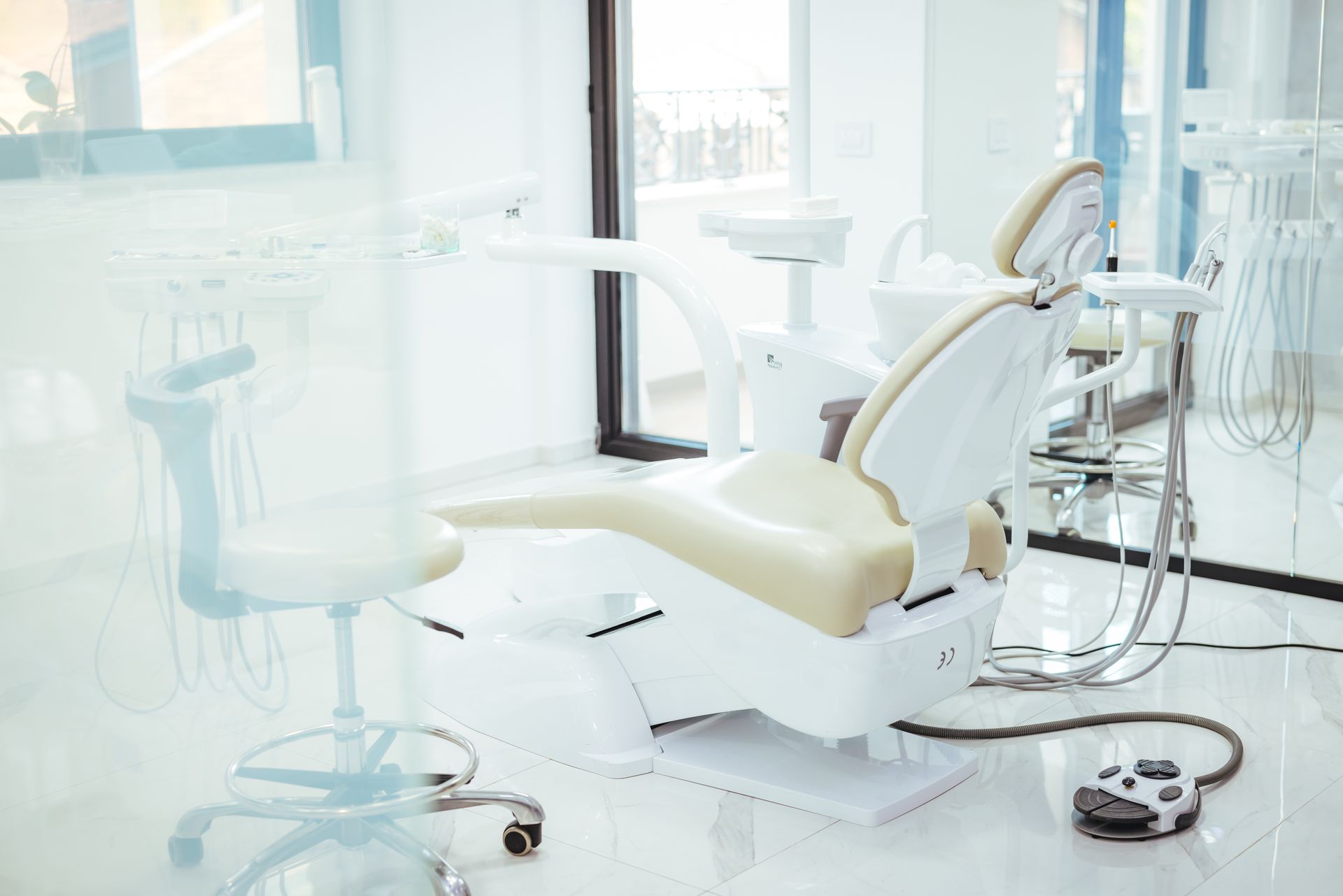 Fauteuil dentaire moderne dans une clinique lumineuse et stérile, avec instruments et tabourets à proximité.