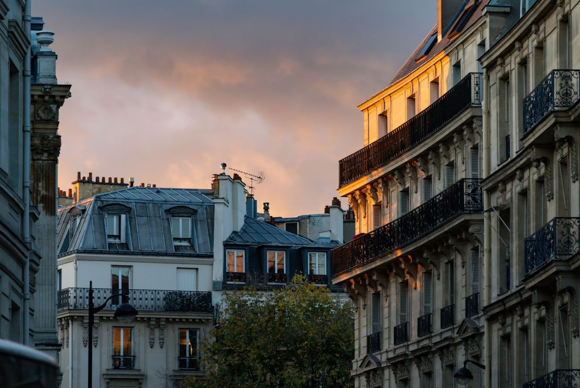 Vue des immeubles parisiens du 17e arrondissement au coucher du soleil, la lumière dorée frappant les balcons ornés et les façades en pierre.