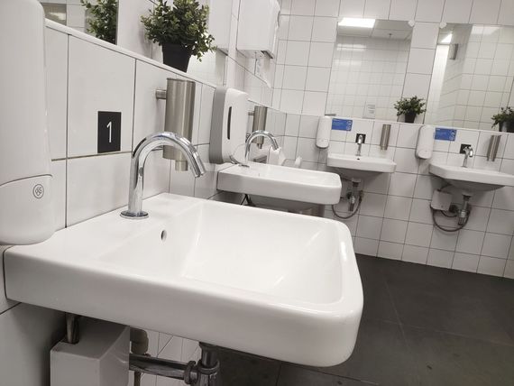 Des lavabos blancs avec robinets chromés contre un mur carrelé blanc.