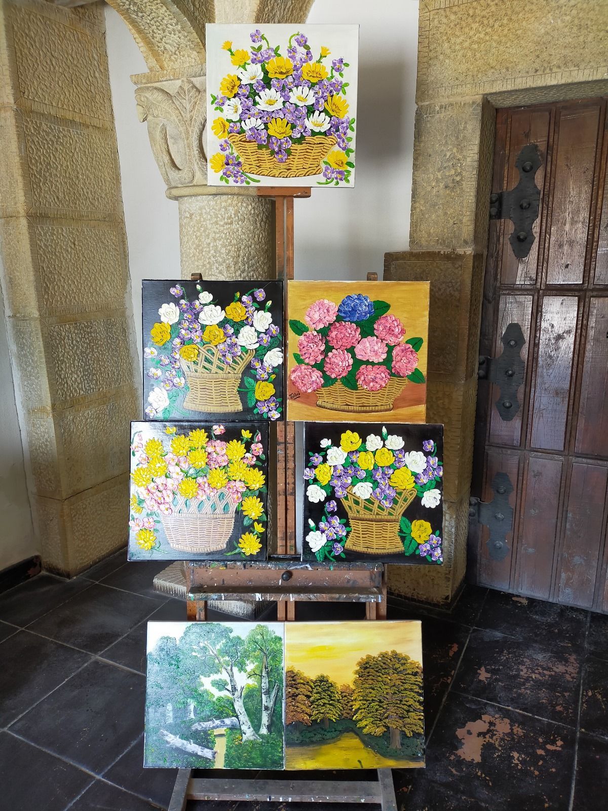 Se exhiben cuatro cuadros de flores en un caballete.