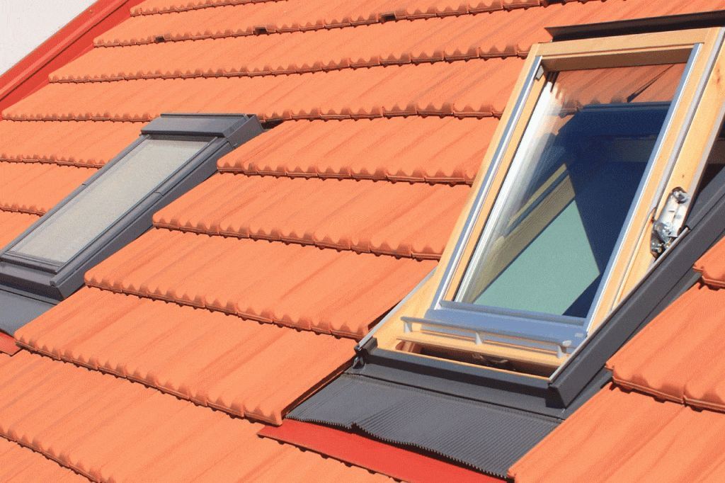 Toit en tuiles orange avec deux puits de lumière, l'un ouvert, l'autre fermé.