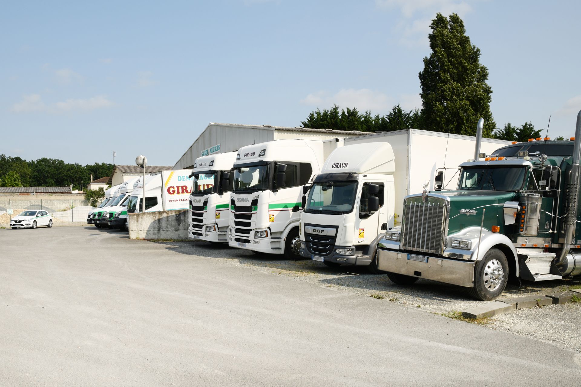 Une rangée de semi-remorques et de véhicules commerciaux de toutes sortes, stationnés sur un terrain gravillonné par une journée ensoleillée.