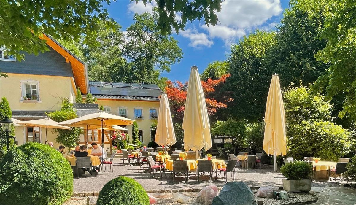 Ein Restaurant mit Tischen und Stühlen und Sonnenschirmen davor