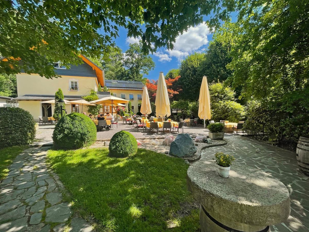 Eine Terrasse mit Tischen und Sonnenschirmen vor einem Haus