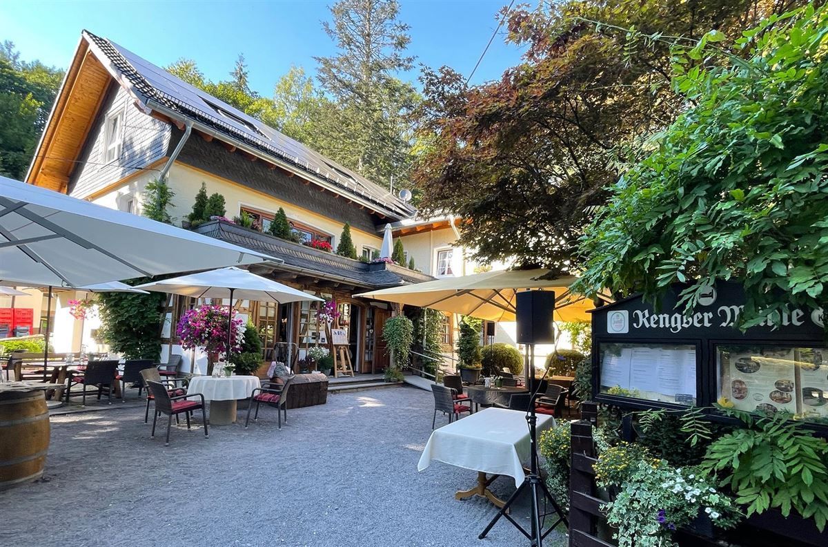 Ein Restaurant mit Tischen und Sonnenschirmen davor