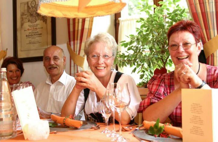 Eine Gruppe von Leuten sitzt mit Gläsern Wein an einem Tisch.