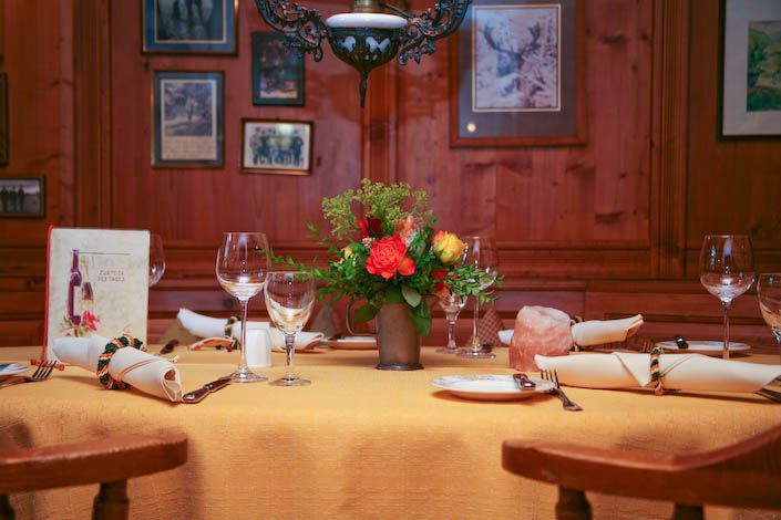 Ein Tisch mit einer Vase mit Blumen und Weingläsern darauf