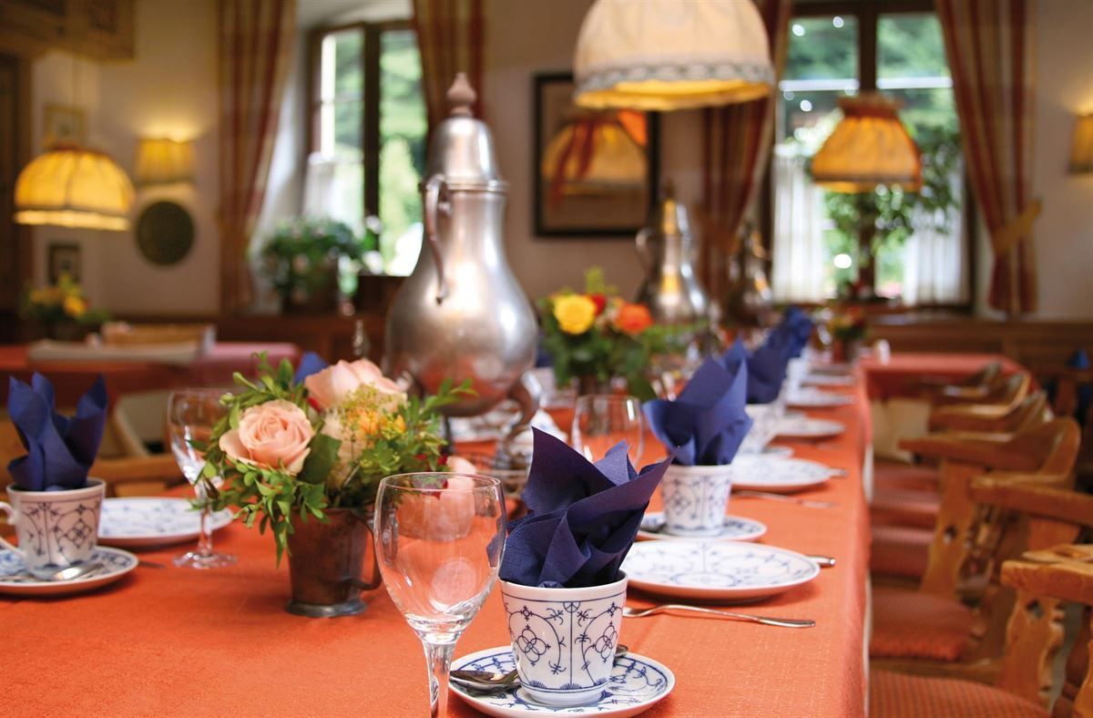 Ein langer Tisch mit Tellern, Gläsern und Blumen darauf