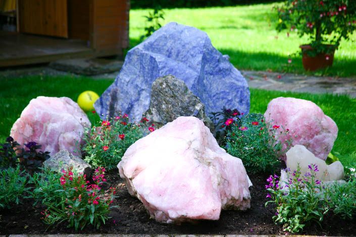 Ein Garten mit rosa und blauen Steinen und Blumen