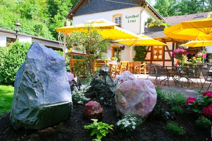Ein großer Felsen liegt vor einem Restaurant mit gelben Sonnenschirmen