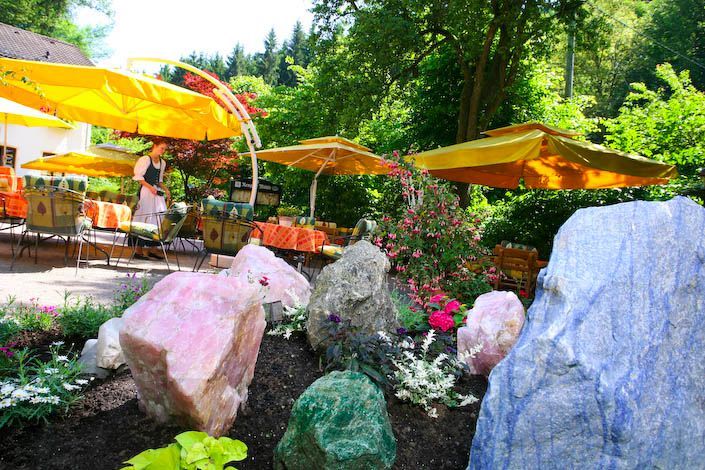 Ein Garten mit Felsen und Blumen und Sonnenschirmen im Hintergrund
