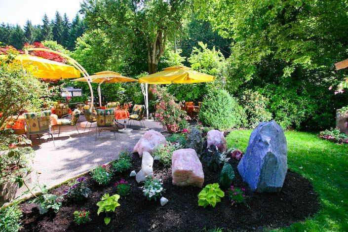 Ein Garten mit Felsen, Blumen und Sonnenschirmen