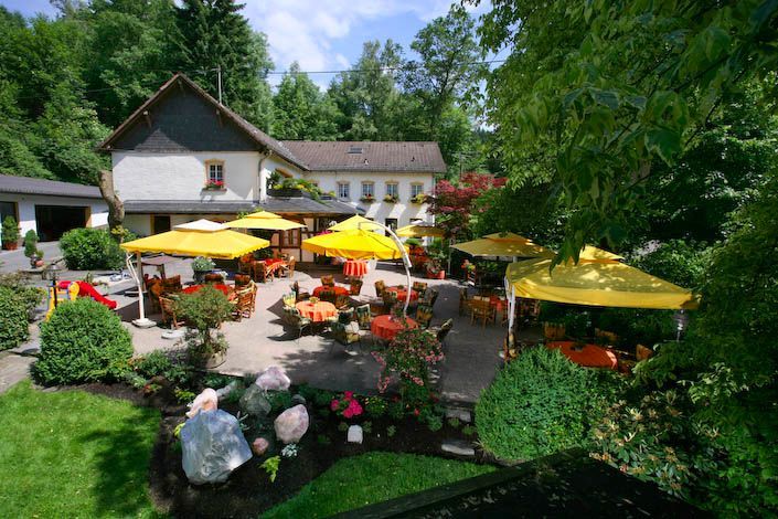 Eine Terrasse mit gelben Sonnenschirmen und Tischen vor einem Haus