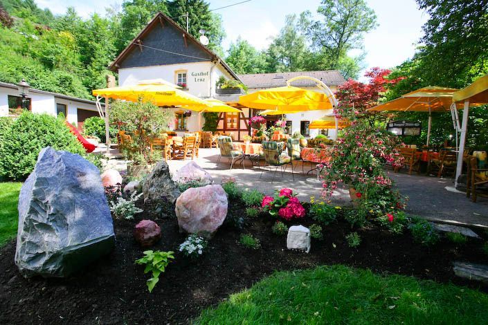 Ein Garten mit Blumen und Sonnenschirmen vor einem Haus