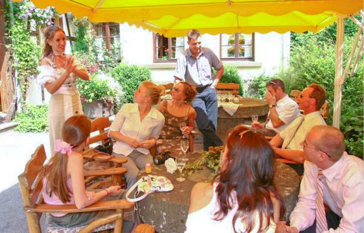 Eine Gruppe von Menschen sitzt um einen Tisch unter einem Sonnenschirm