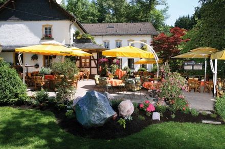 Eine Terrasse mit gelben Sonnenschirmen und Tischen vor einem Haus