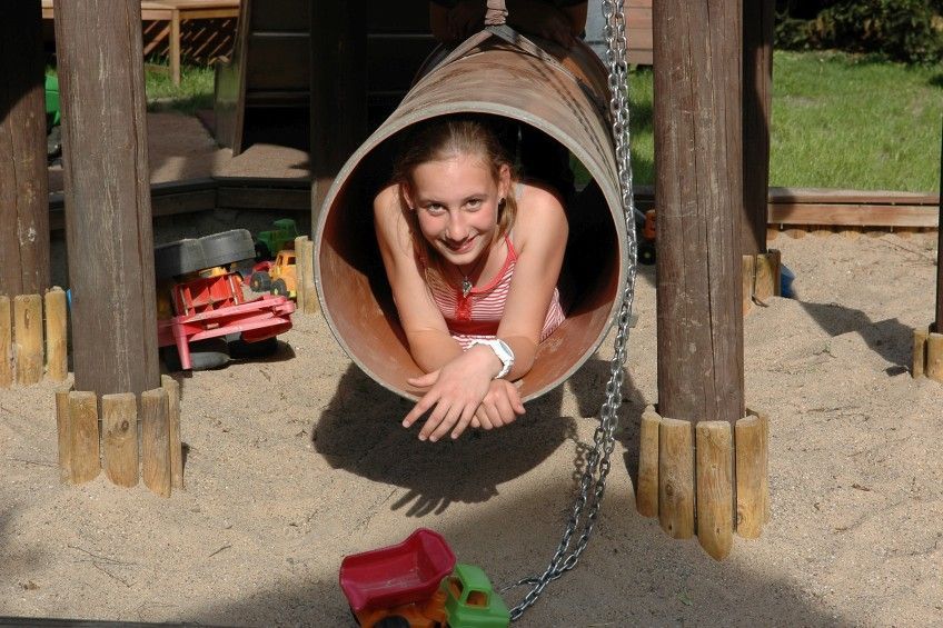 Ein junges Mädchen liegt in einem Tunnel auf einem Spielplatz