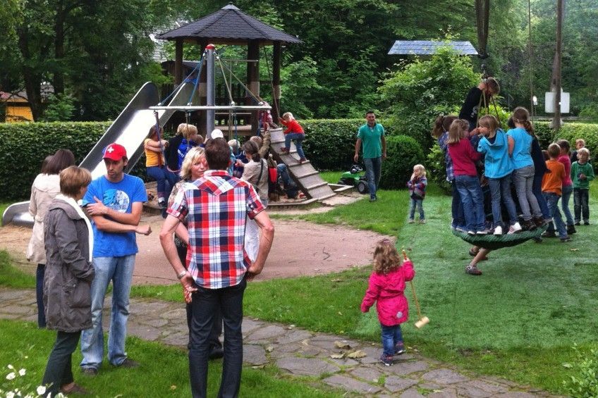Eine Gruppe von Menschen steht auf einem Spielplatz herum