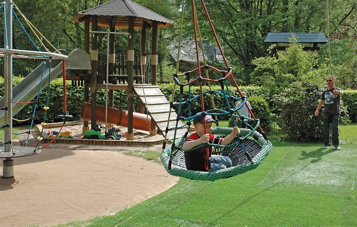 Ein Kind sitzt auf einer Schaukel auf einem Spielplatz