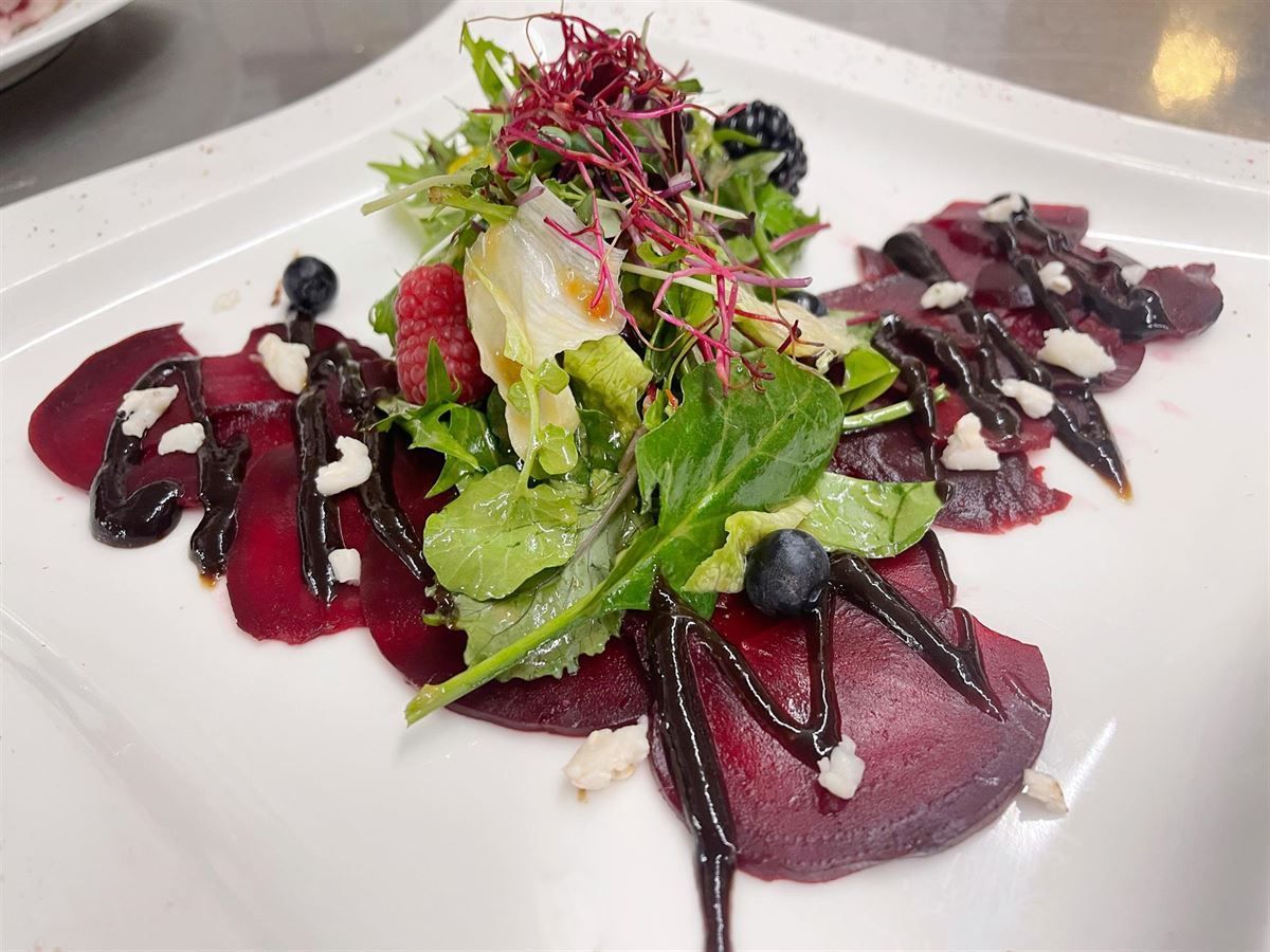 Ein weißer Teller mit Salat und Rüben