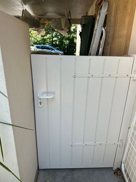 Une porte blanche avec une poignée blanche se trouve à côté d'un mur.