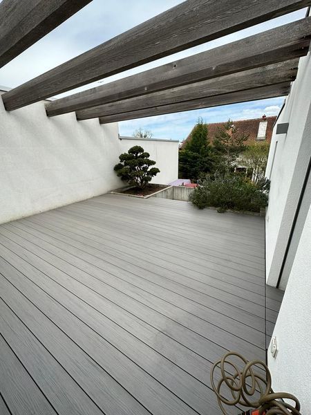Une terrasse avec une pergola et un tuyau dessus