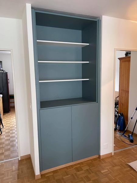 Une bibliothèque bleue avec des étagères et des portes dans une pièce.