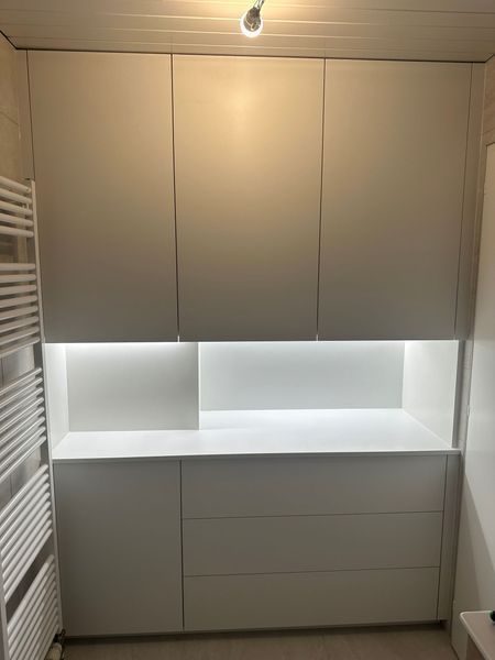 Une salle de bain avec des armoires et des tiroirs blancs et un porte-serviettes.