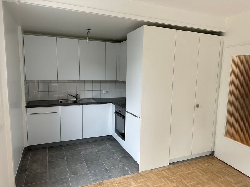 Une cuisine avec des armoires blanches et des comptoirs noirs