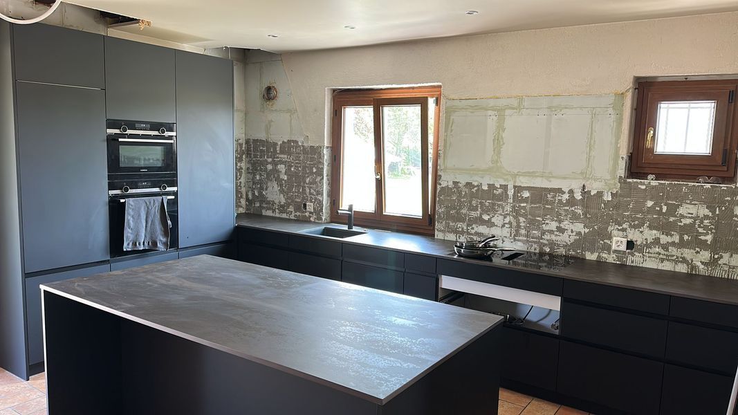 Une cuisine avec des armoires noires et un grand îlot au milieu.