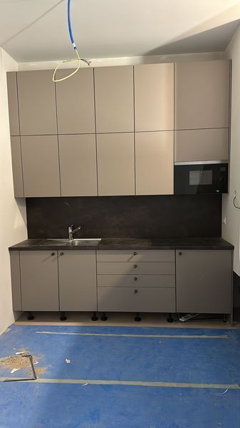 Une cuisine avec un évier, des armoires, des tiroirs et un micro-ondes.