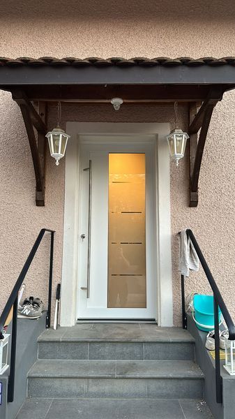 La porte d'entrée d'une maison avec des escaliers et un auvent au-dessus.