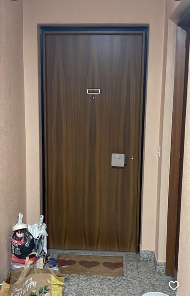 Une porte en bois se trouve dans un couloir à côté d'un tapis.