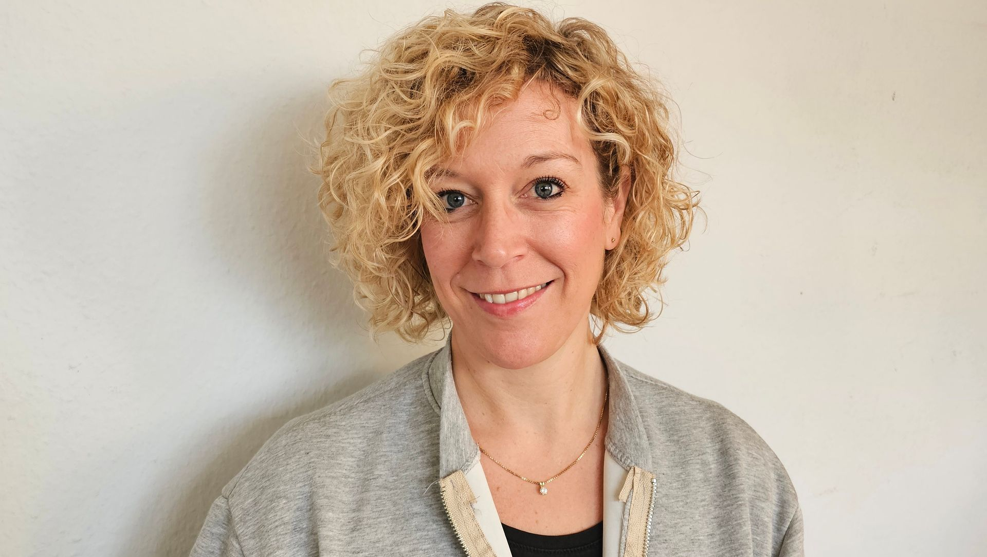 Eine Frau in einem blauen Hemd lächelt in die Kamera