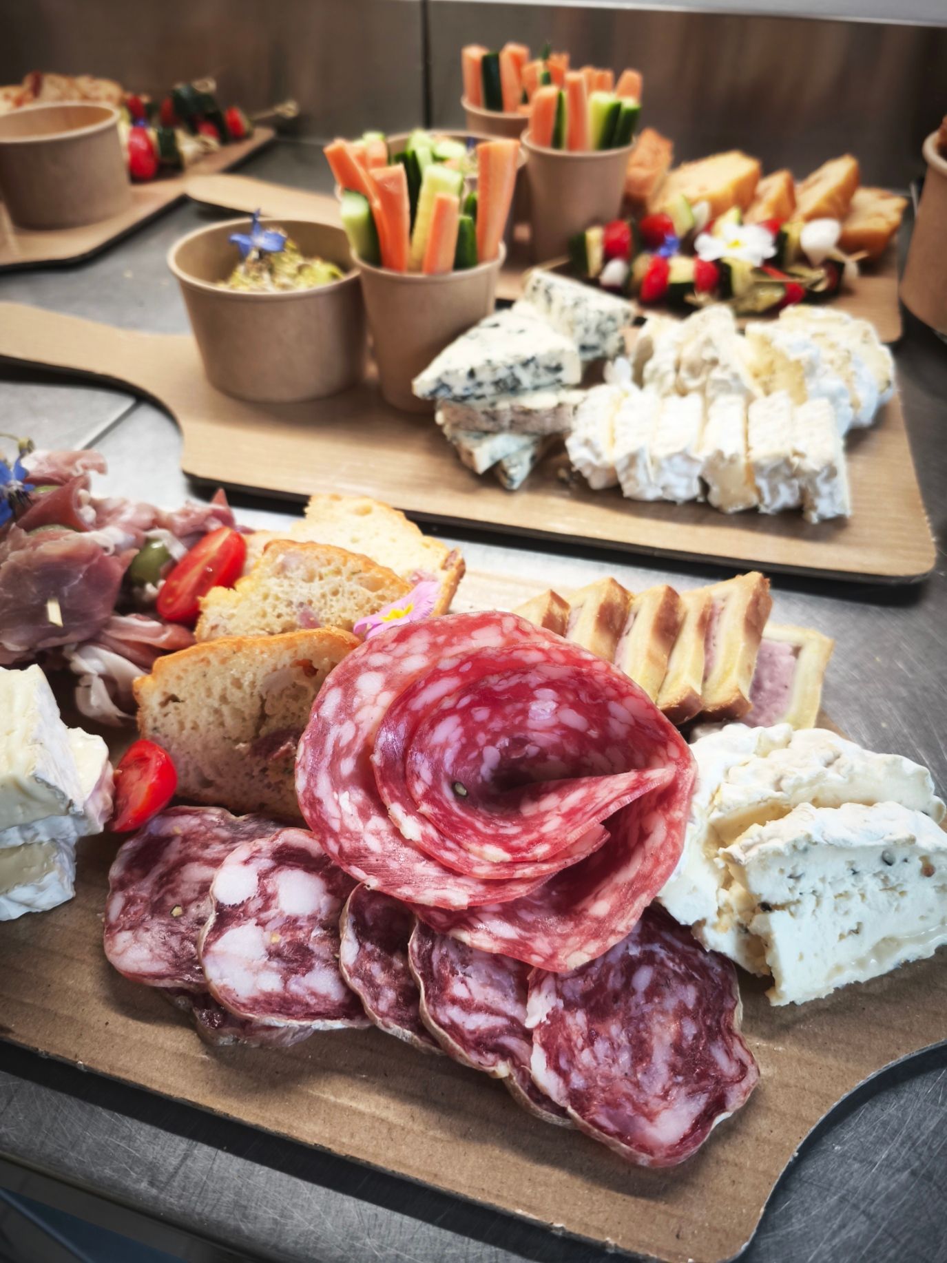 Un plateau de gaufres rectangulaires en amuse-bouche, garnies de crème fouettée, de tranches de fruits et de morceaux de cornichons.