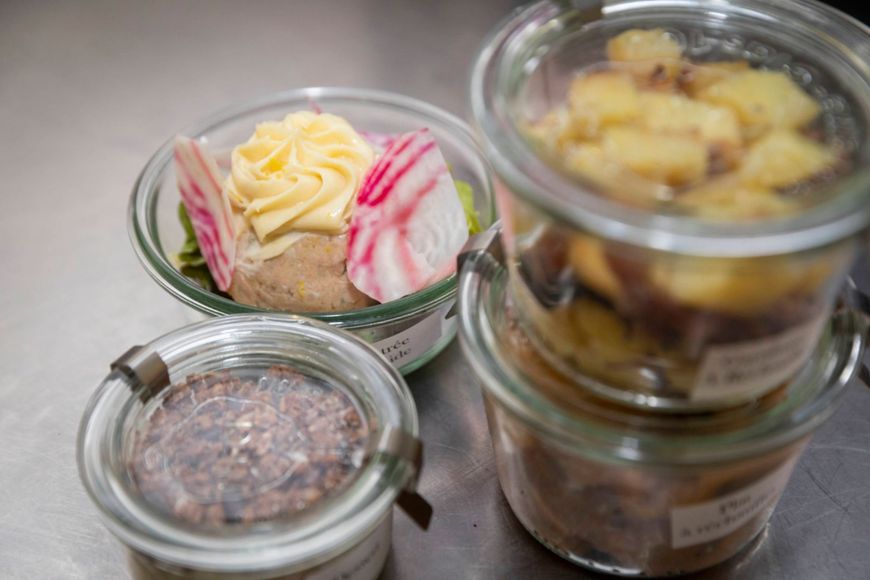 Gros plan sur deux petits bols carrés blancs remplis de toasts salés, garnis de saumon fumé, de crème et de garnitures colorées.