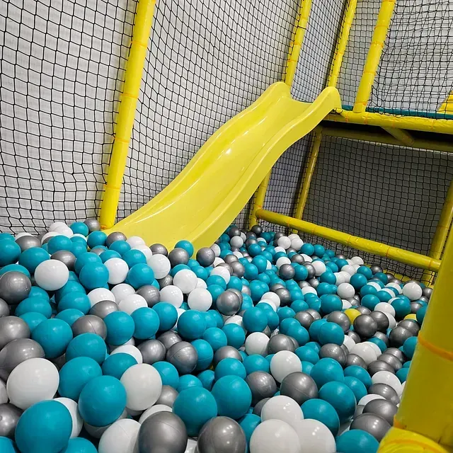 Un tobogán en una piscina de pelotas lleno de pelotas azules, blancas y grises.