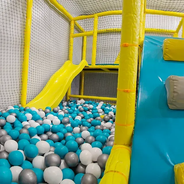 Hay un tobogán en el medio de una piscina de pelotas llena de pelotas azules y blancas.