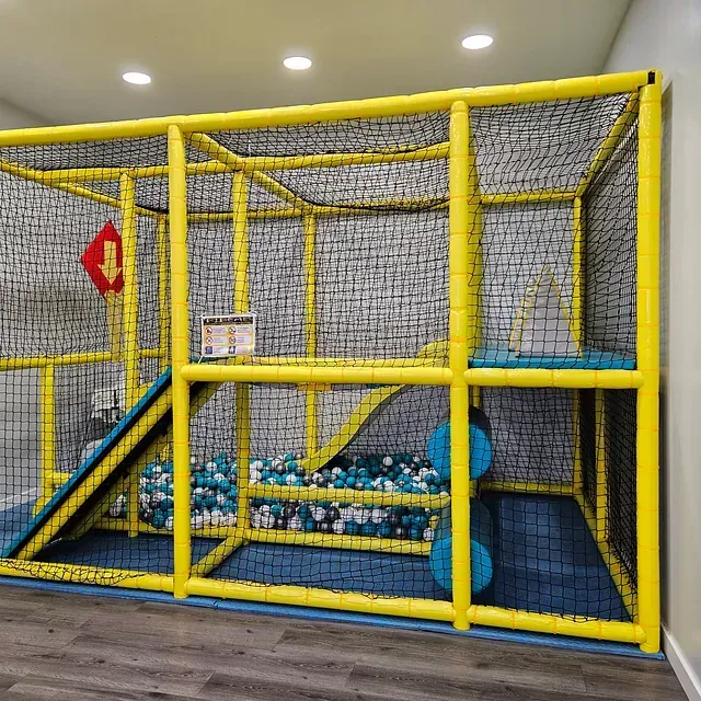 Una gran jaula amarilla llena de bolas azules y blancas en una habitación.