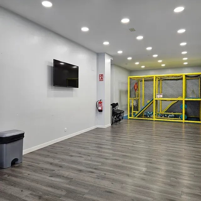 Una habitación grande con pisos de madera y un televisor en la pared.