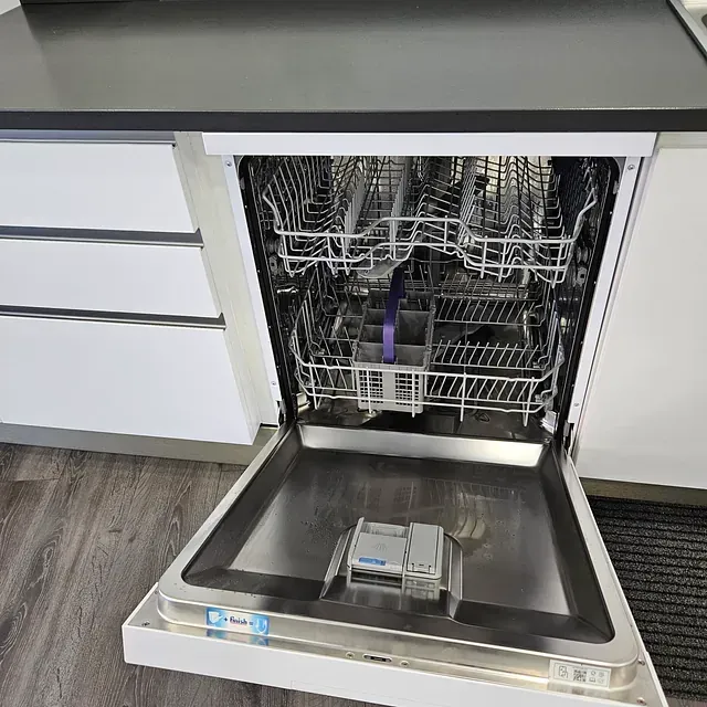 Un lavavajillas está abierto en una cocina con la puerta abierta.