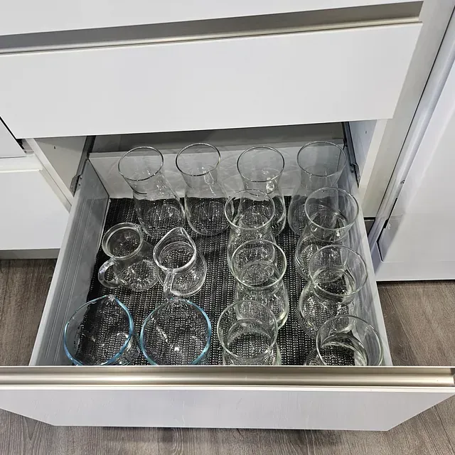 Un cajón lleno de copas de vino y tazas en una cocina.