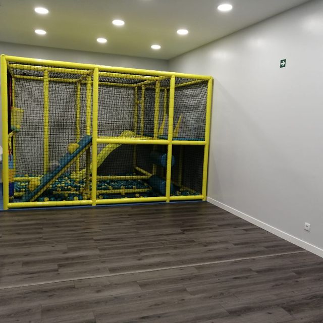 Una habitación vacía con una jaula amarilla y un tobogán.