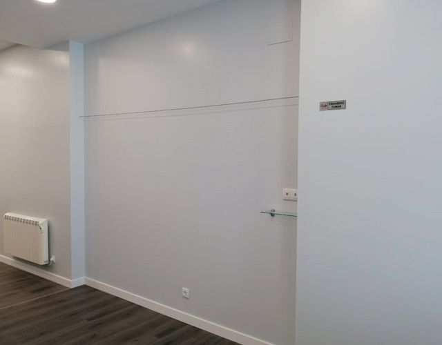 Un pasillo con una pared blanca y un radiador.