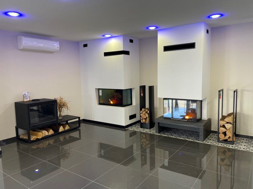 Showroom avec deux cheminées, carrelage noir et climatisation.