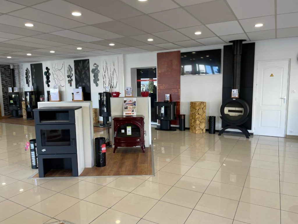 Salle d'exposition présentant une variété de cheminées et de poêles sur un sol carrelé.